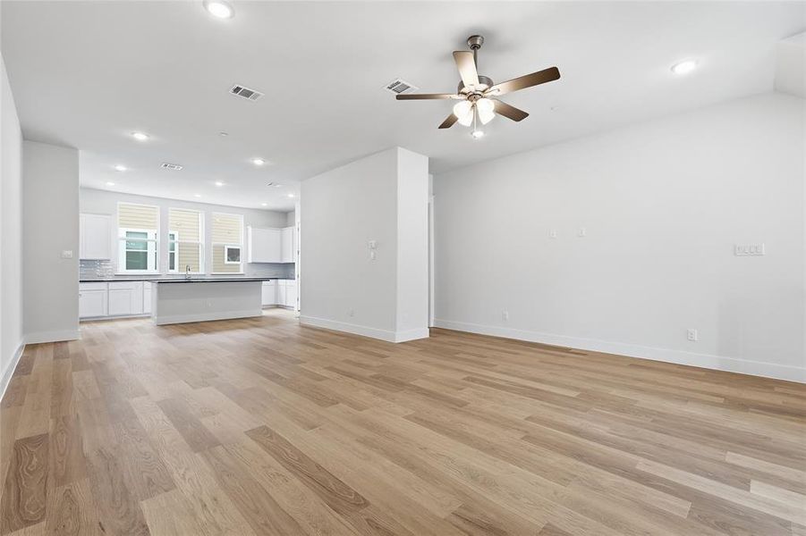 Expansive living area with light wood flooring, recessed lighting, and a ceiling fan