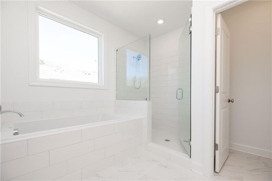 The primary suite offers a large soaking tub and separate frameless, tile shower.