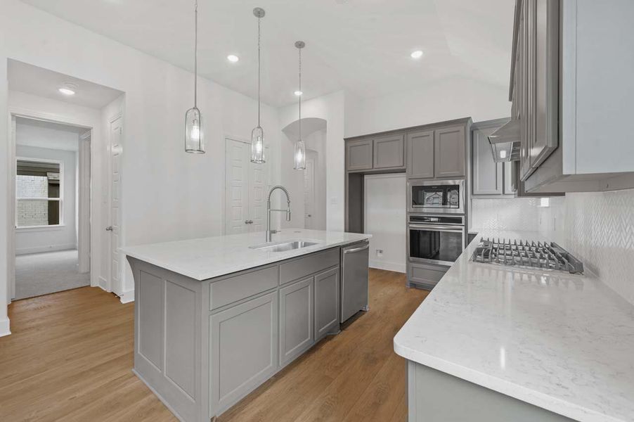 Kitchen featuring light wood-type flooring, gray cabinetry, appliances with stainless steel finishes, and a sink