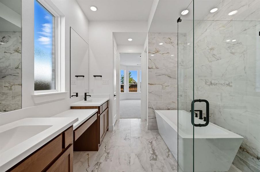 Bathroom featuring light marble finish flooring, two vanities, a freestanding bath, tile walls, and recessed lighting Bathroom featuring light marble finish flooring, two vanities, a freestanding bath, tile walls, and recessed lighting