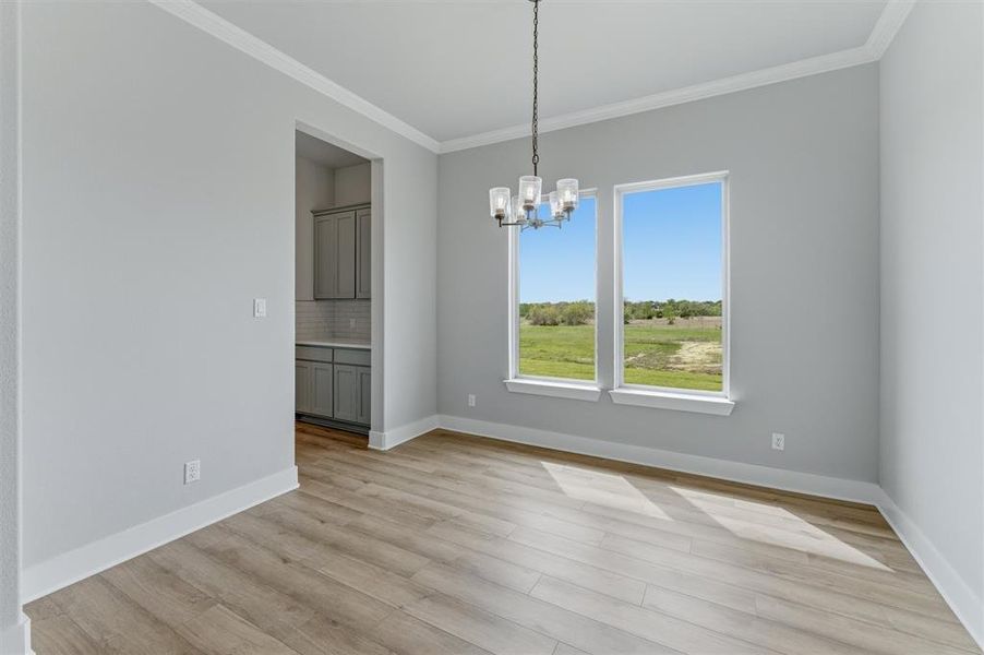 Unfurnished dining area featuring a chandelier, ornamental molding, and light wood-style floors