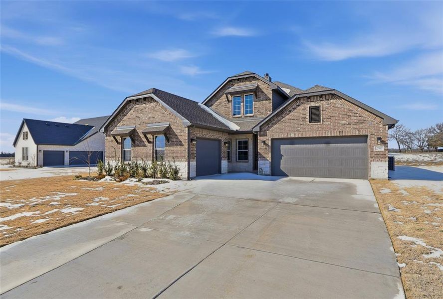 View of front of home with brick siding, an attached garage, driveway, and a shingled roof