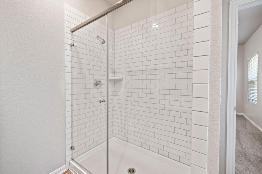 Bathroom featuring a shower stall and a textured wall Bathroom featuring a shower stall and a textured wall