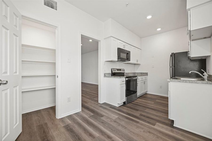 Kitchen with dark hardwood / wood-like flooring, sink, electric stove, white cabinetry, and fridge