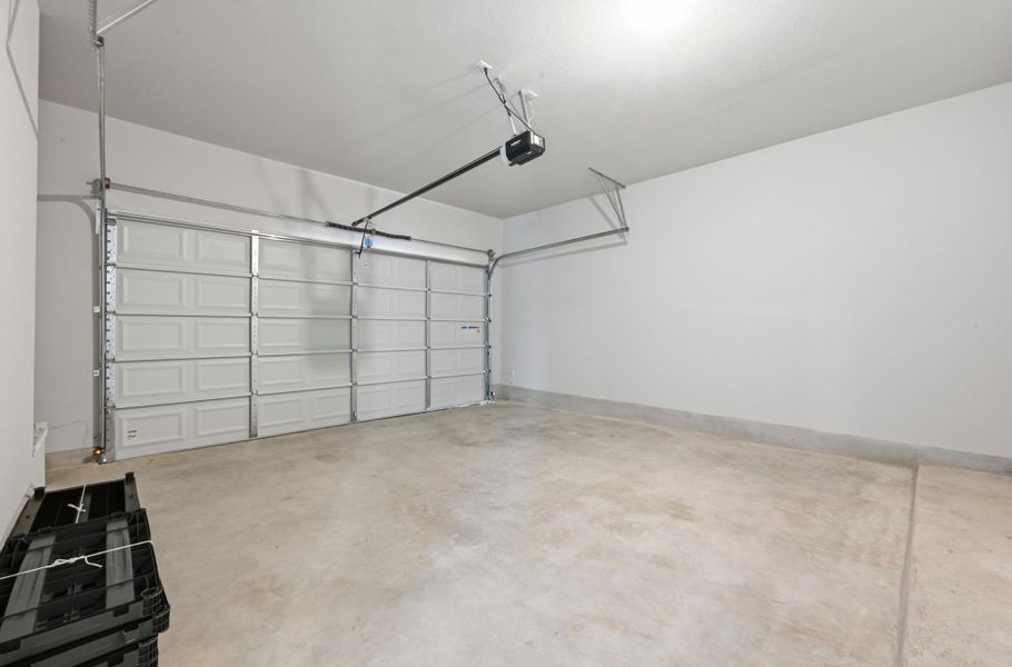 Garage interior featuring a sectional garage door, automatic opener, concrete flooring, and painted walls Garage interior featuring a sectional garage door, automatic opener, concrete flooring, and painted walls