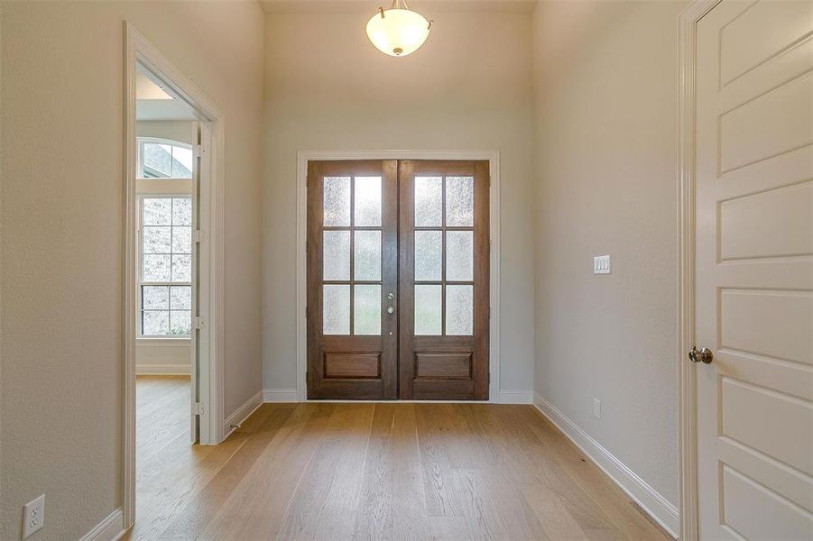 Foyer entrance with light hardwood / wood-style flooring and french doors