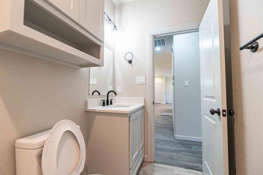 Bathroom featuring vanity, a textured wall, and light wood-style floors