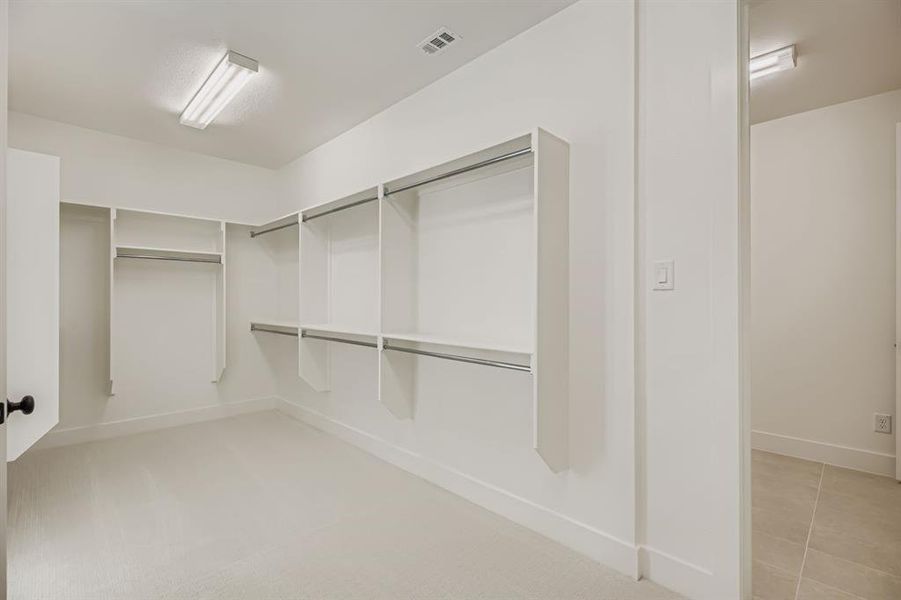 Walk in closet with light tile patterned floors and light colored carpet Walk in closet with light tile patterned floors and light colored carpet