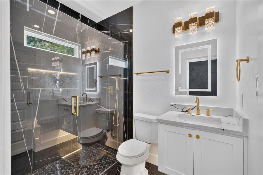 Contemporary bathroom featuring a frameless glass shower enclosure, black marble-look wall tiling, and a hexagon-tiled shower floor