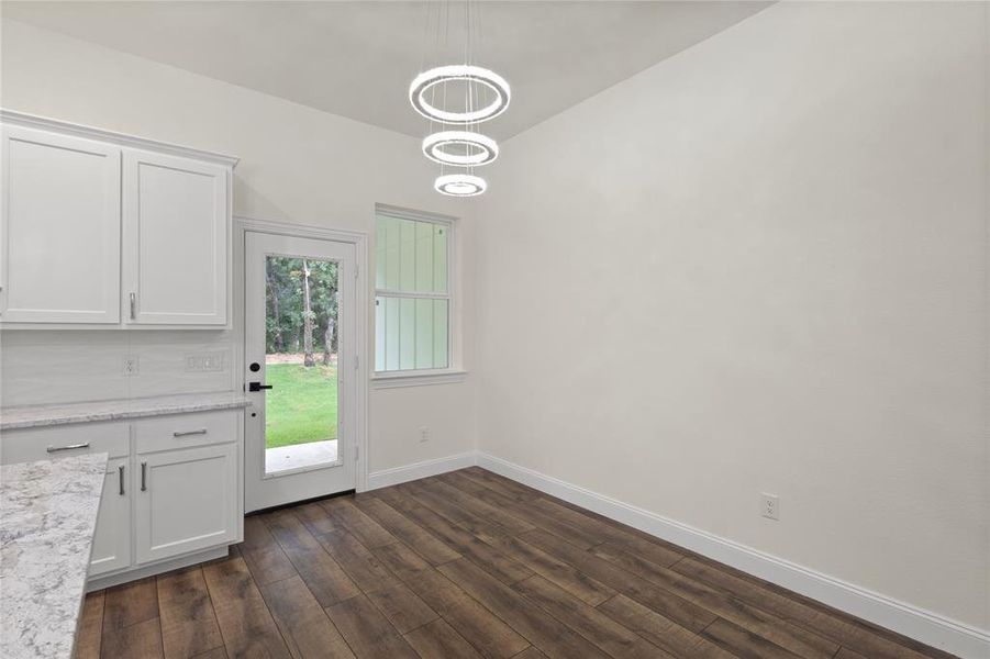 Kitchen dining area featuring wood-finish flooring and a contemporary tiered chandelier Kitchen dining area featuring wood-finish flooring and a contemporary tiered chandelier