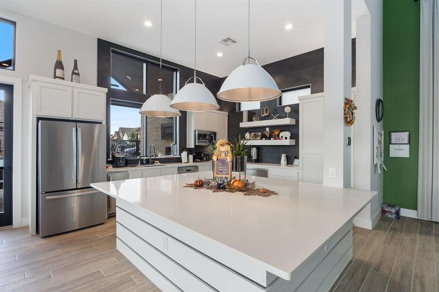 Kitchen in community clubhouse featuring white cabinetry, stainless steel appliances, hanging light fixtures, light wood-style flooring, and recessed lighting