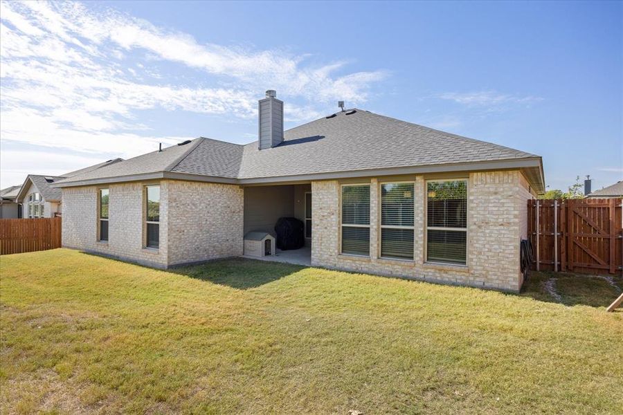 Back of property with a fenced backyard, a shingled roof, a chimney, a patio area, and brick siding