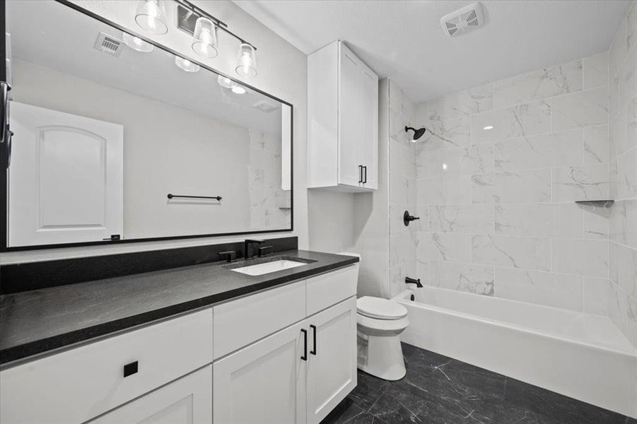Bathroom with marble look tile flooring, vanity, and bathing tub / shower combination