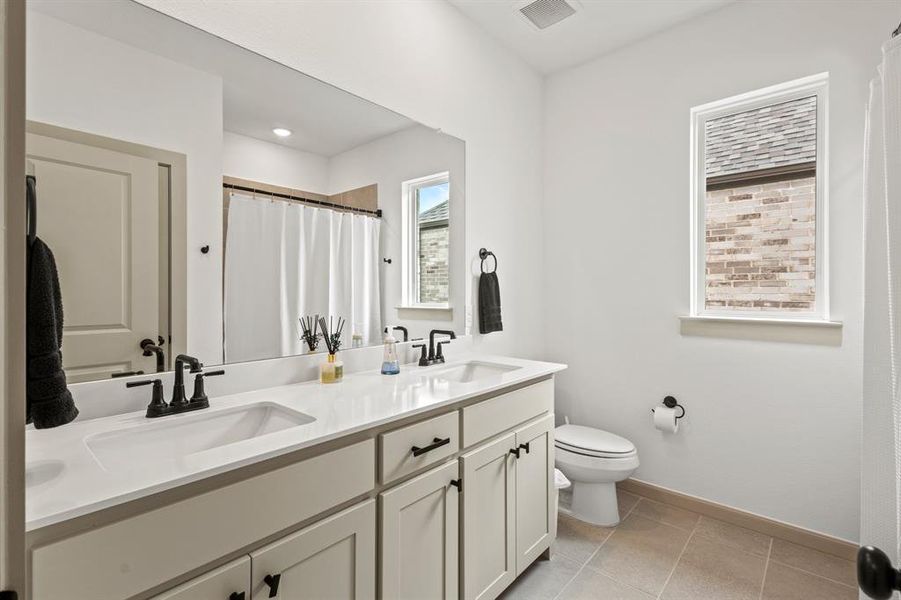 Bathroom featuring double vanity, tile patterned flooring, and a shower with shower curtain