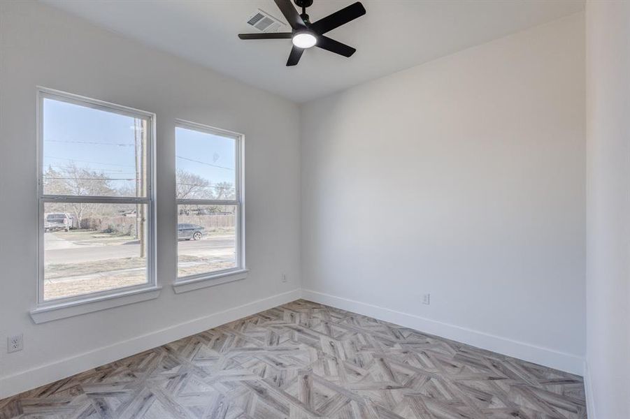 Empty room featuring light parquet flooring, a wealth of natural light, and ceiling fan