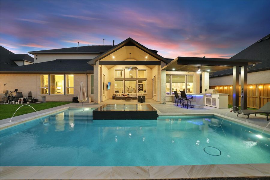 The pool's elegant water features create a peaceful ambiance, enhancing the backyard retreat both day and night.