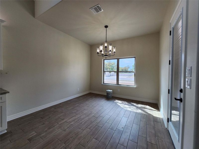 Unfurnished dining area with wood finish floors and a chandelier