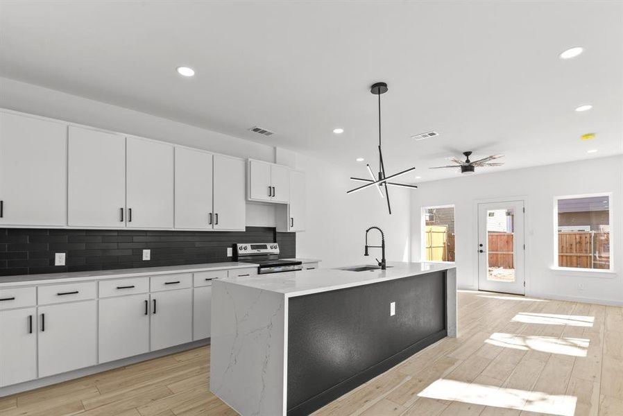 Kitchen featuring electric range, a sink, visible vents, light wood-style floors, and backsplash