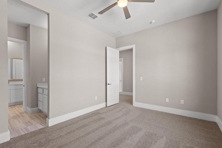A spacious bedroom with fresh carpeting, featuring a ceiling fan and convenient access to a private bathroom. A spacious bedroom with fresh carpeting, featuring a ceiling fan and convenient access to a private bathroom.
