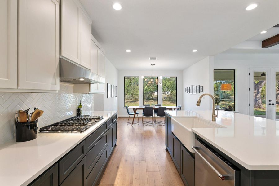 Kitchen with recessed lighting, appliances with stainless steel finishes, hanging light fixtures, light wood finished floors, and decorative backsplash