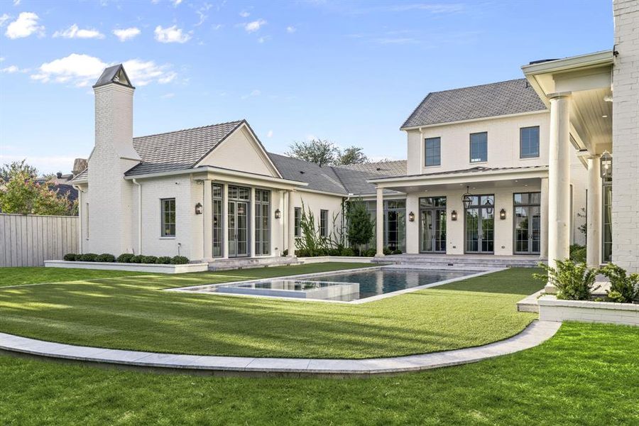 Rear view of house featuring a patio, brick siding, a pool with connected hot tub, a yard, and a chimney Rear view of house featuring a patio, brick siding, a pool with connected hot tub, a yard, and a chimney