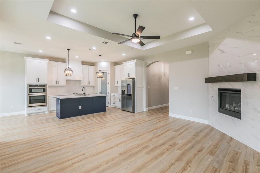 Kitchen with open floor plan, stainless steel appliances, light wood-style floors, ceiling fan, and white cabinets Kitchen with open floor plan, stainless steel appliances, light wood-style floors, ceiling fan, and white cabinets