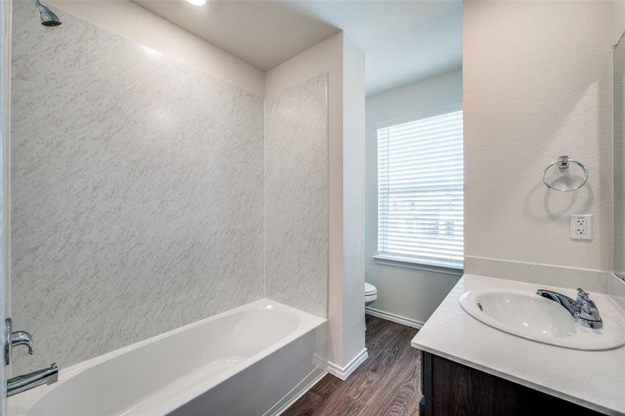 Full bathroom featuring hardwood / wood-style floors, vanity, bathing tub / shower combination, and toilet