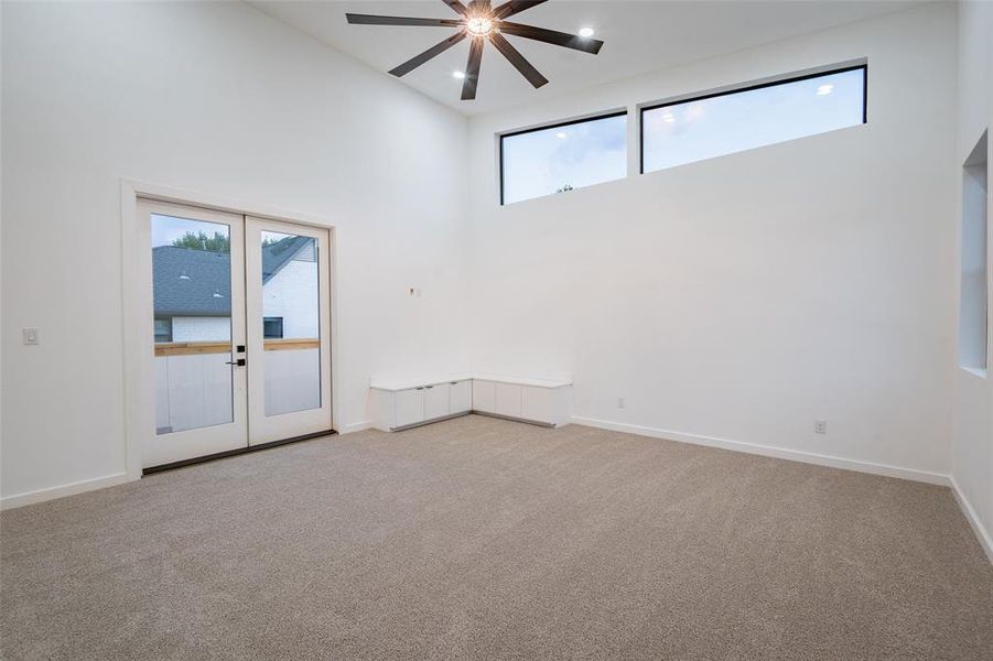 Massive game room featuring french doors, a towering ceiling, and a wealth of natural light