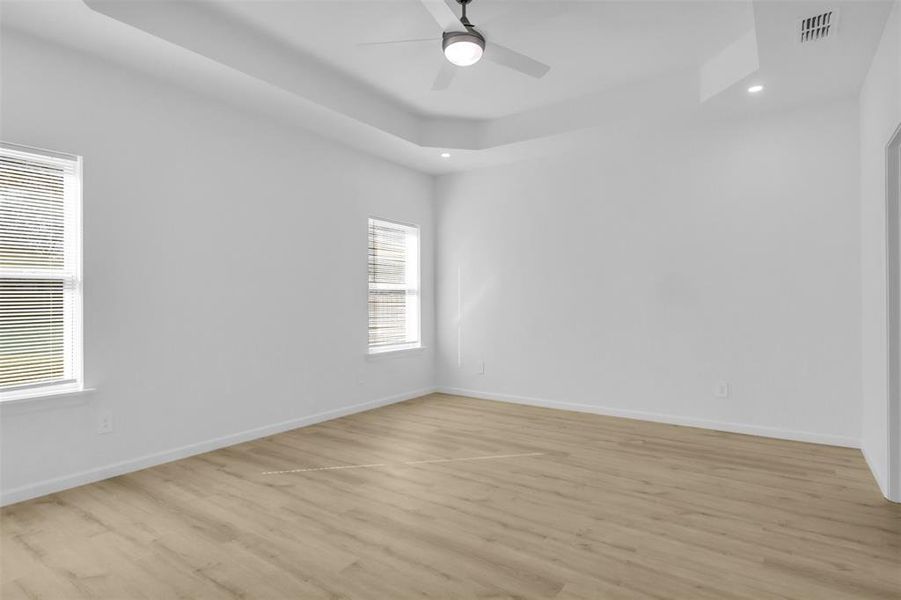 Unfurnished room featuring a tray ceiling, recessed lighting, light wood-style floors, and a ceiling fan