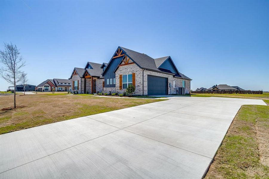 View of front of house featuring a front yard, driveway, a residential view, an attached garage, and stone siding View of front of house featuring a front yard, driveway, a residential view, an attached garage, and stone siding