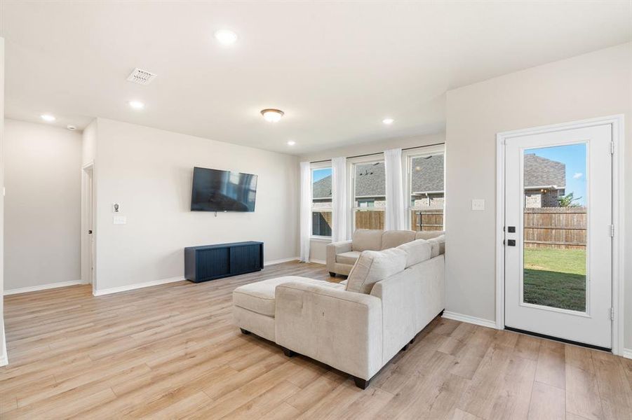 Living room with healthy amount of natural light, light wood-style flooring, and recessed lighting Living room with healthy amount of natural light, light wood-style flooring, and recessed lighting