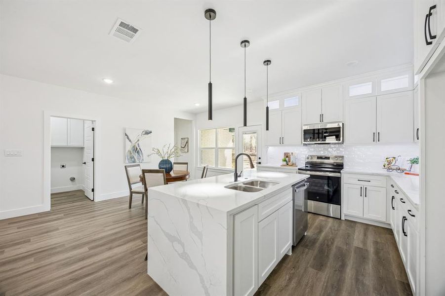 Kitchen featuring a waterfall island and a peek into the laundry room.