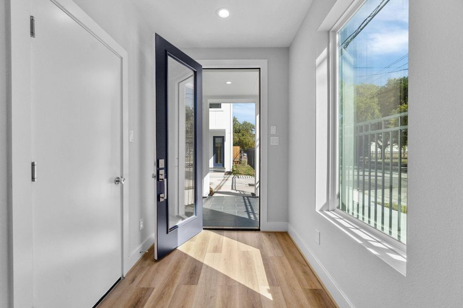 Inviting entryway with wide plank flooring, natural light, and a direct view to the outdoor space, creating an open and welcoming first impression.