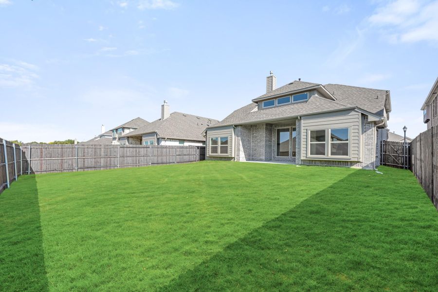 Backyard of brick home with large green lawn and wood privacy fence Backyard of brick home with large green lawn and wood privacy fence