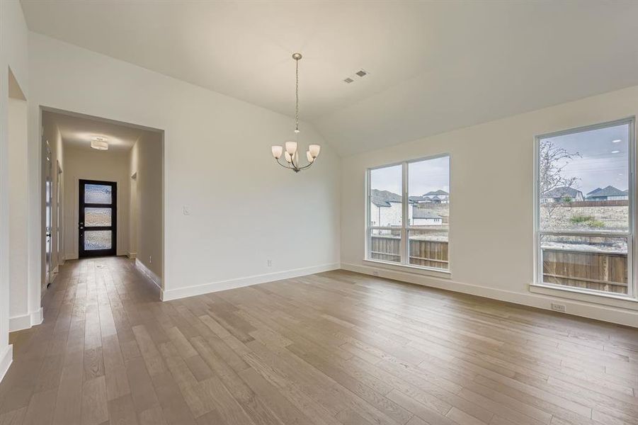 Unfurnished dining area with light wood-type flooring, lofted ceiling, and a chandelier Unfurnished dining area with light wood-type flooring, lofted ceiling, and a chandelier
