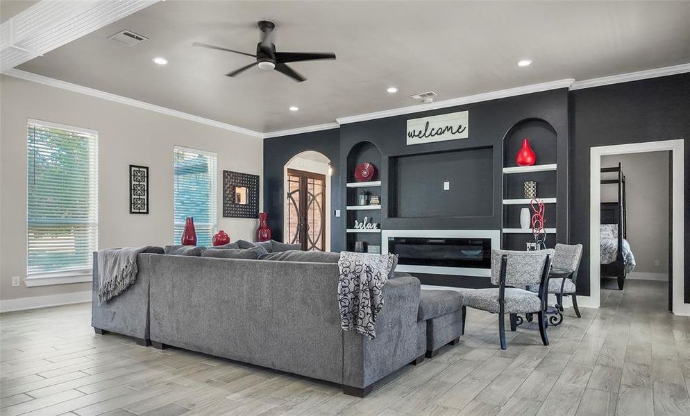 Living room featuring ornamental molding, a ceiling fan, light wood-style flooring, and recessed lighting