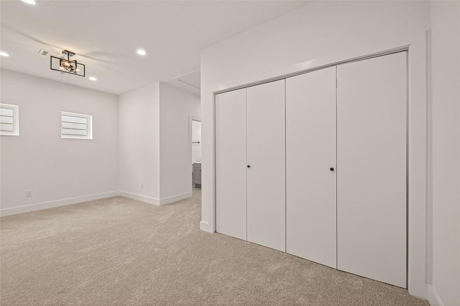This photo showcases a spacious, modern bedroom with neutral carpet, ample closet space, and contemporary lighting. The room has a clean, minimalist design with two small windows for natural light. This photo showcases a spacious, modern bedroom with neutral carpet, ample closet space, and contemporary lighting. The room has a clean, minimalist design with two small windows for natural light.