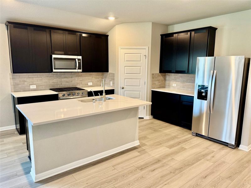 Kitchen featuring appliances with stainless steel finishes, light wood-style floors, backsplash, light countertops, and recessed lighting Kitchen featuring appliances with stainless steel finishes, light wood-style floors, backsplash, light countertops, and recessed lighting