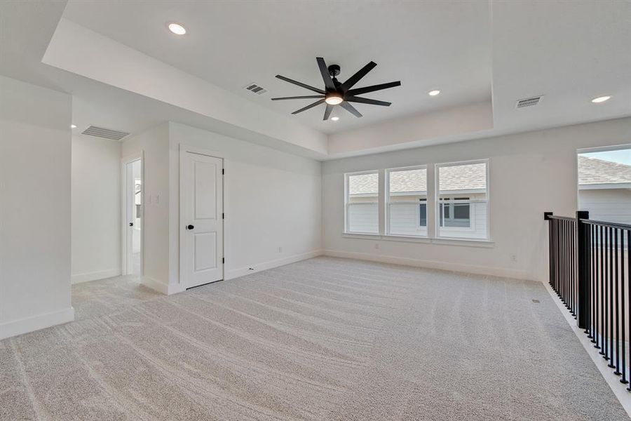 Unfurnished living room featuring a raised ceiling, healthy amount of natural light, light carpet, and recessed lighting Unfurnished living room featuring a raised ceiling, healthy amount of natural light, light carpet, and recessed lighting