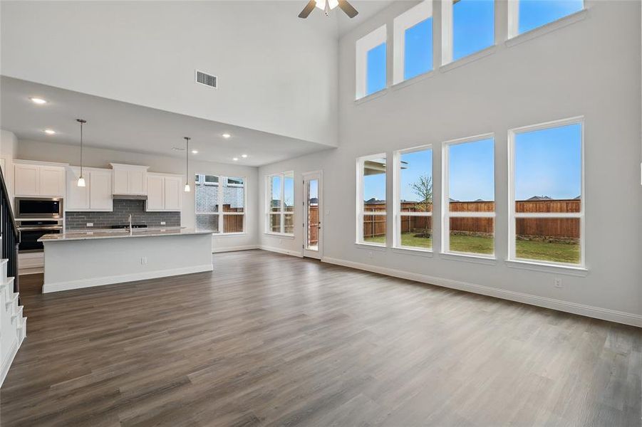 Unfurnished living room with baseboards, a healthy amount of sunlight, ceiling fan, and dark wood finished floors