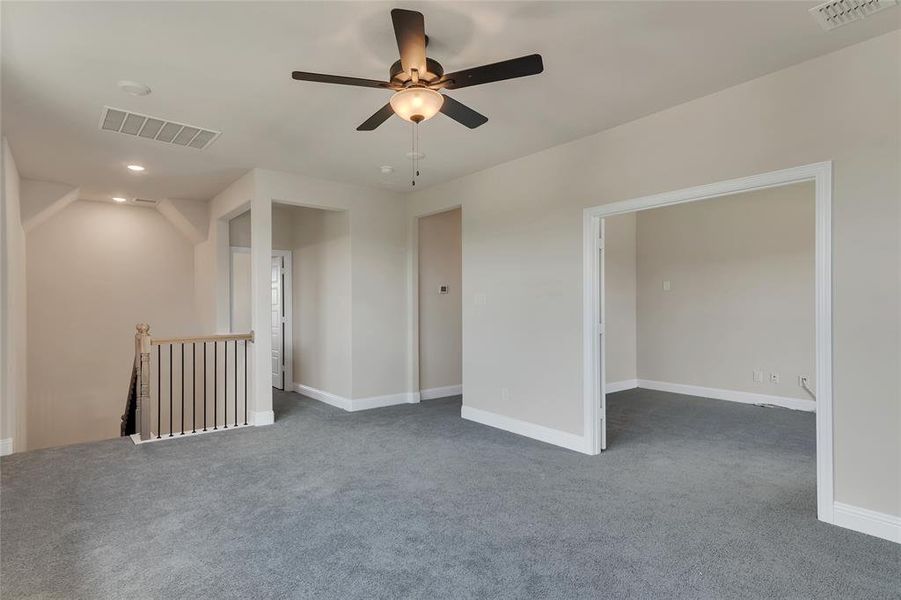 Carpeted spare room featuring lofted ceiling and ceiling fan