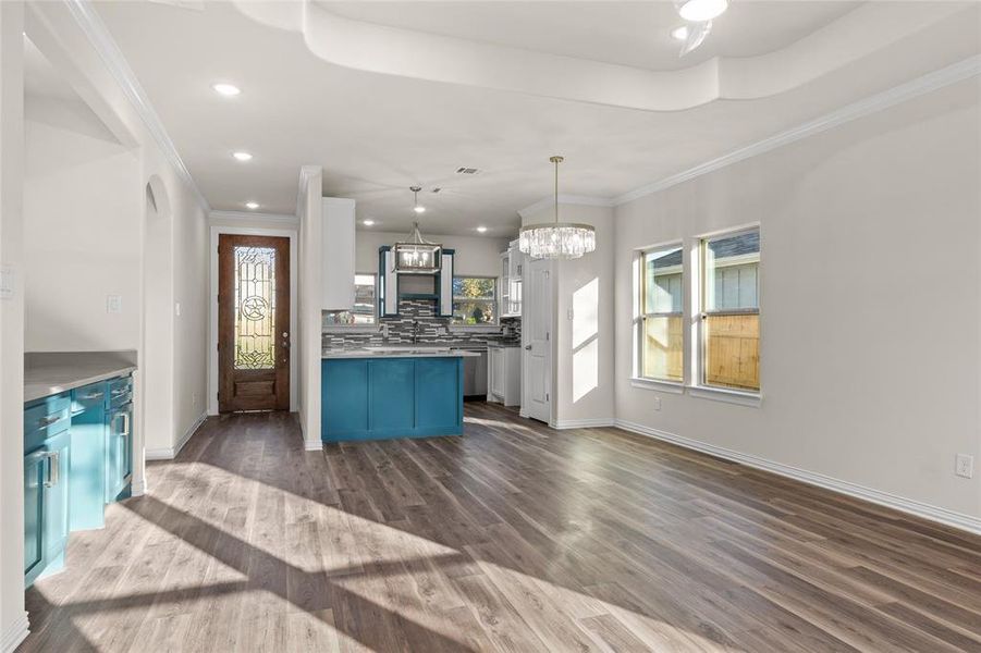 Kitchen featuring blue cabinets, ornamental molding, plenty of natural light, pendant lighting, and backsplash