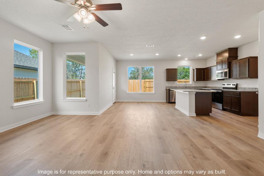 Kitchen with stainless steel appliances, open floor plan, dark wood finish cabinetry, a center island, and a ceiling fan