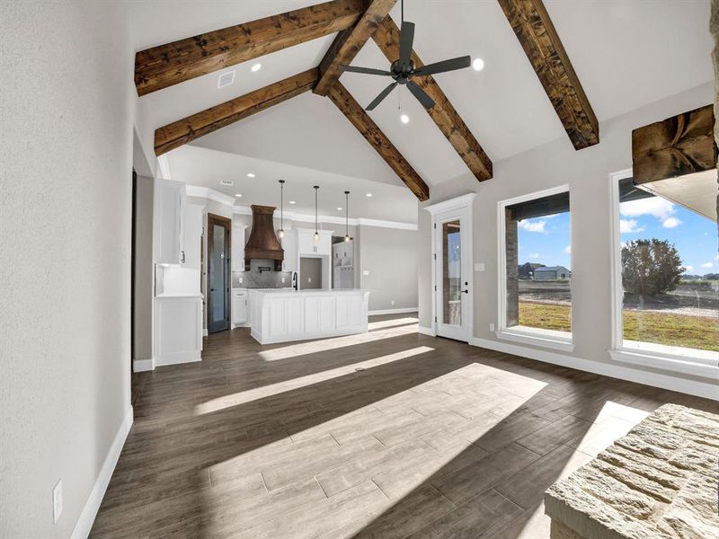 Unfurnished living room featuring ceiling fan, dark hardwood / wood-style flooring, high vaulted ceiling, beamed ceiling, and sink