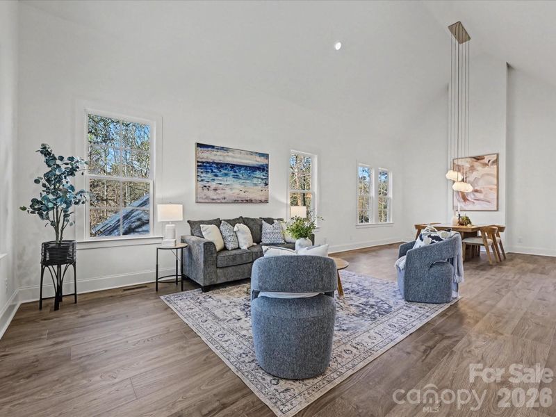 Spacious great room featuring soaring ceilings, abundant natural light, and an open layout that creates an inviting space for relaxing and entertaining.