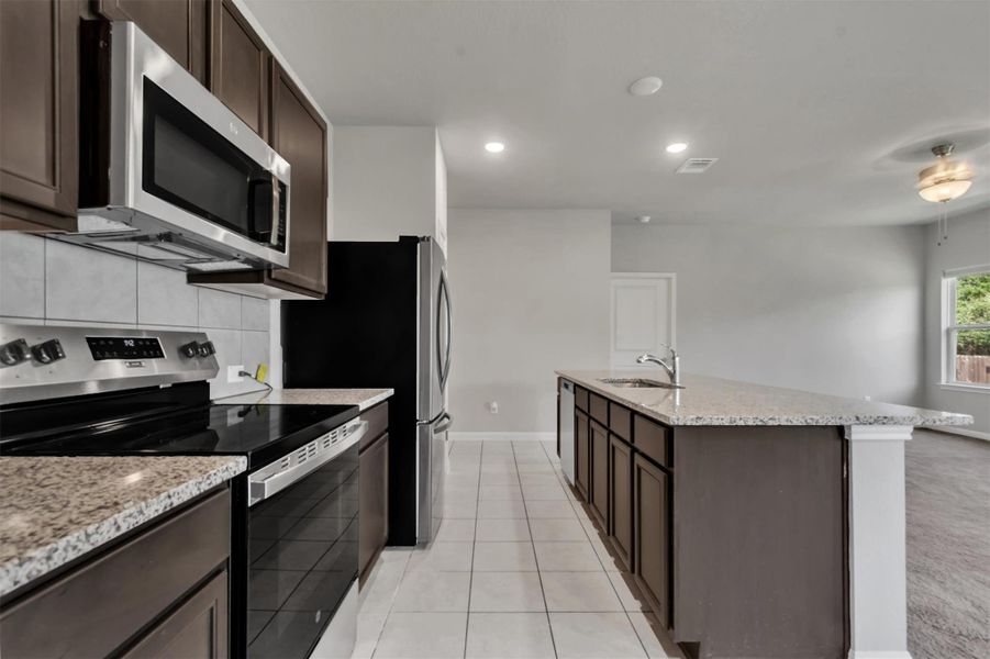A contemporary kitchen showcasing dark wood cabinetry, granite countertops, and modern stainless steel appliances.