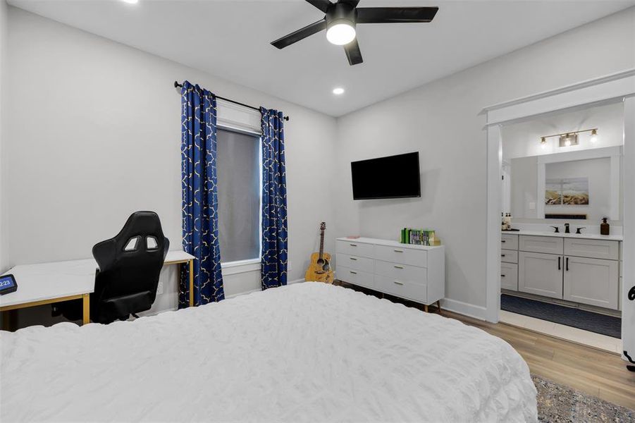 Bedroom with connected bathroom, light hardwood / wood-style floors, ceiling fan, and sink