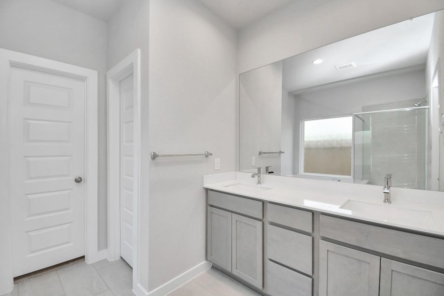 Escape to a spa-like oasis in this primary bathroom. Enjoy a walk-in shower with tile surround, a separate garden tub with custom detailing, and an elegant vanity featuring light countertops, modern hardware, and beautiful recessed lights. Experience luxury and relaxation in every detail.