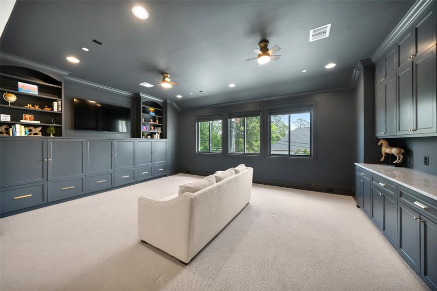 The large, color-drenched game room is located on the second floor, complete with built-in storage, a countertop, and windows that overlook the backyard.
