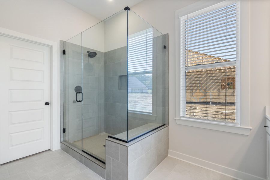 Walk-in shower with tile surround, glass enclosure, built-in bench, and black fixtures Walk-in shower with tile surround, glass enclosure, built-in bench, and black fixtures